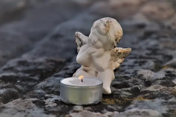 Aniołek z płonącą świecą, symbolizujący poczucie winy po śmierci bliskiej osoby.
