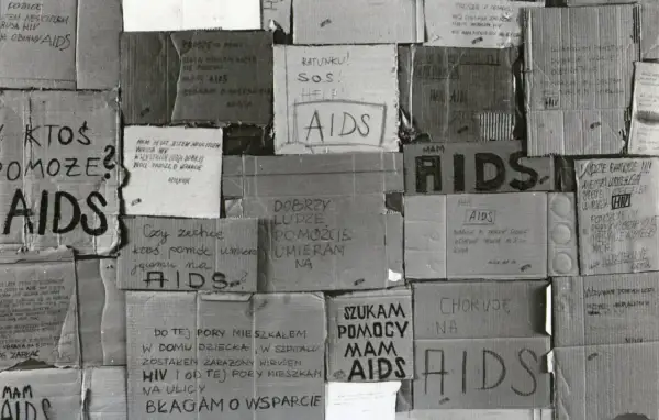 Dwóch mężczyzn rozmawia, jeden w szarym dresie, drugi w różowej koszuli.